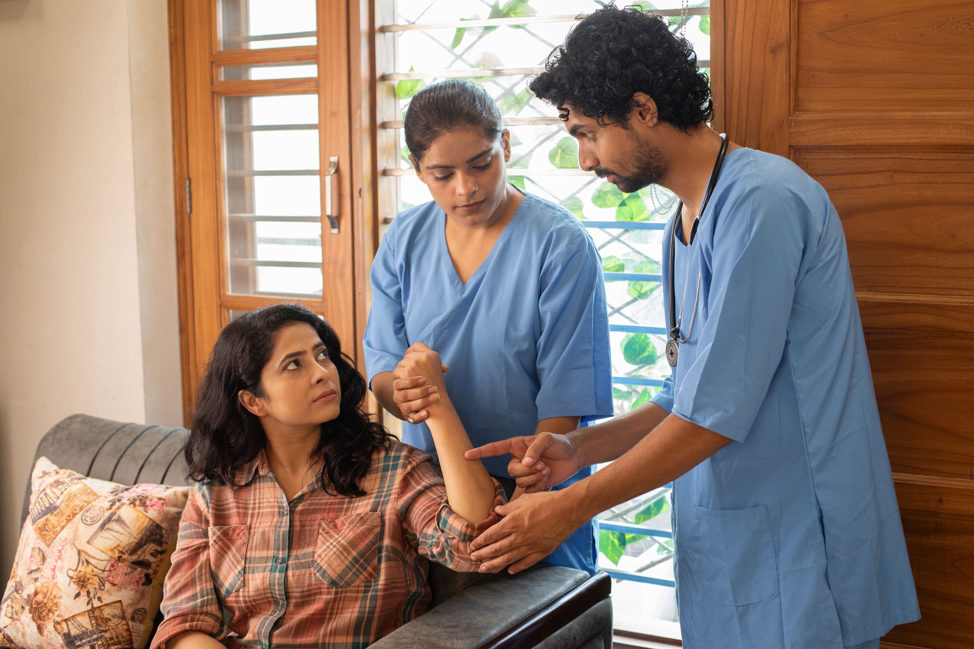 Physiotherapists examining female patient's hand at home